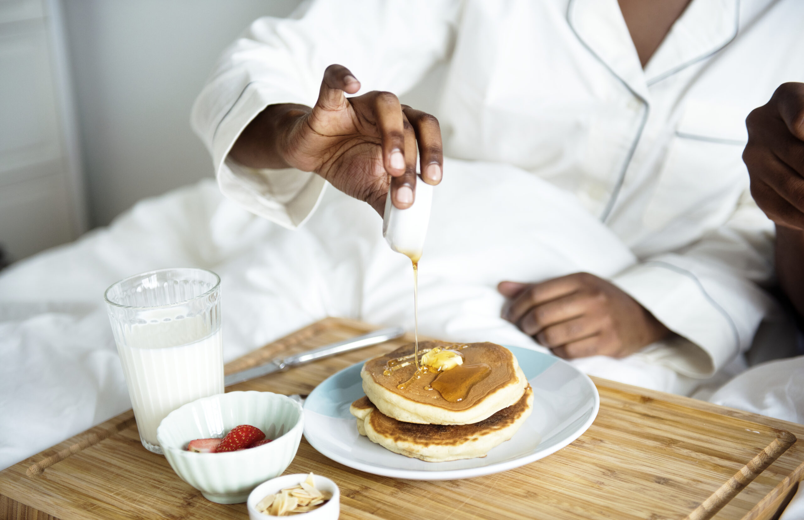 Woman pours maple syrup on her pancakes