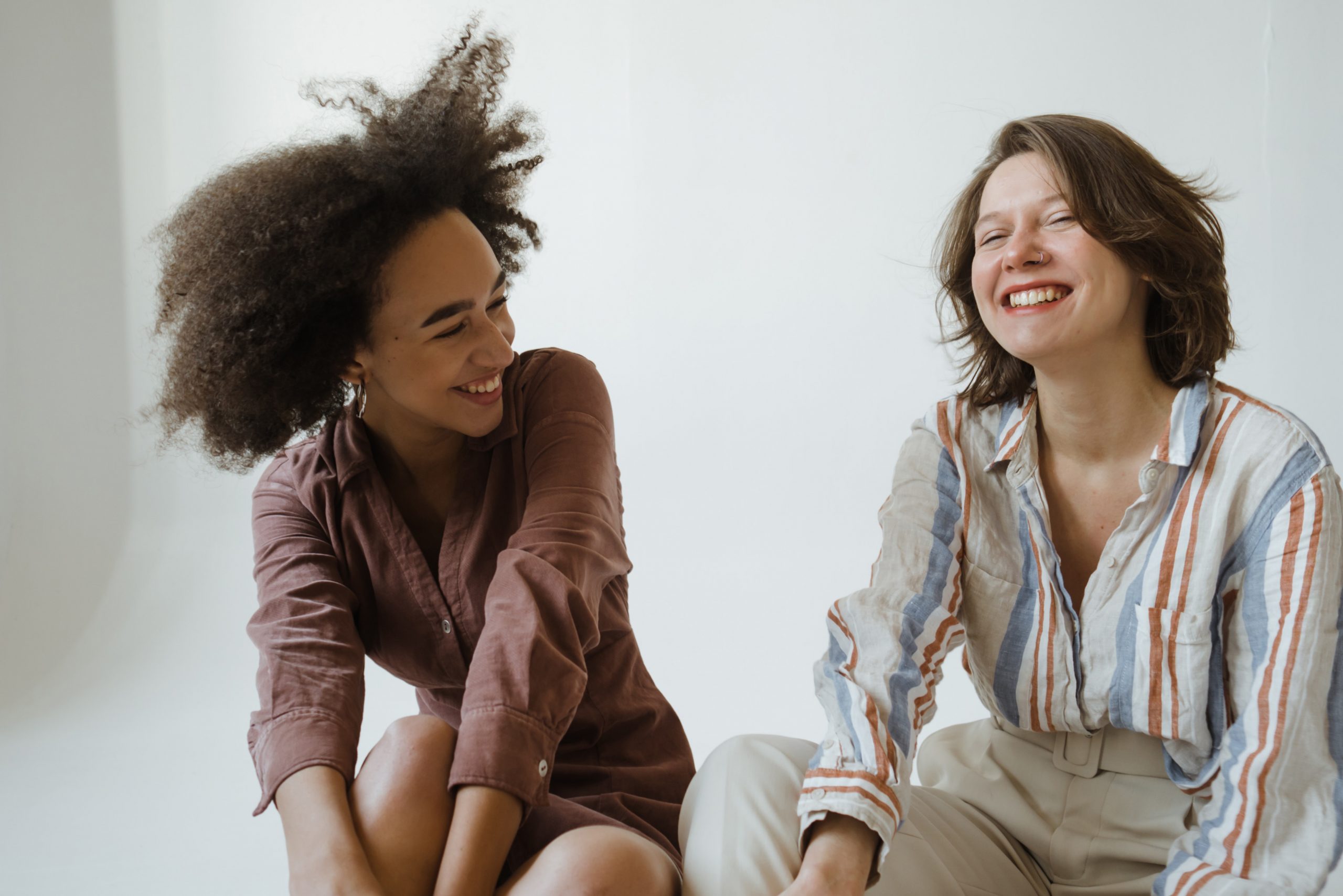 Two young women - one black, one white - share a moment, laughing together. 