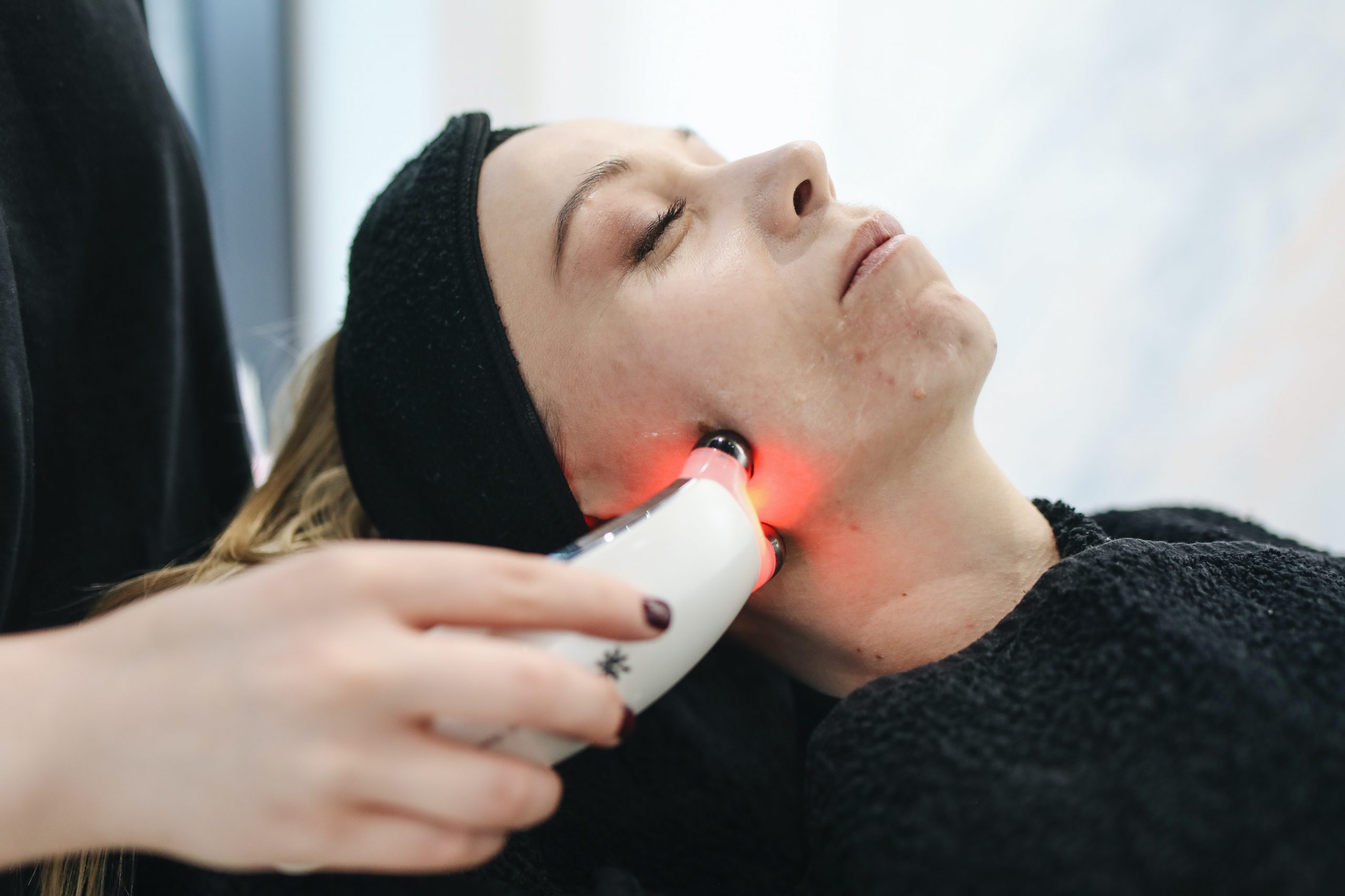 A woman undergoes treatment with the NuFACE Trinity, a facial toning device.