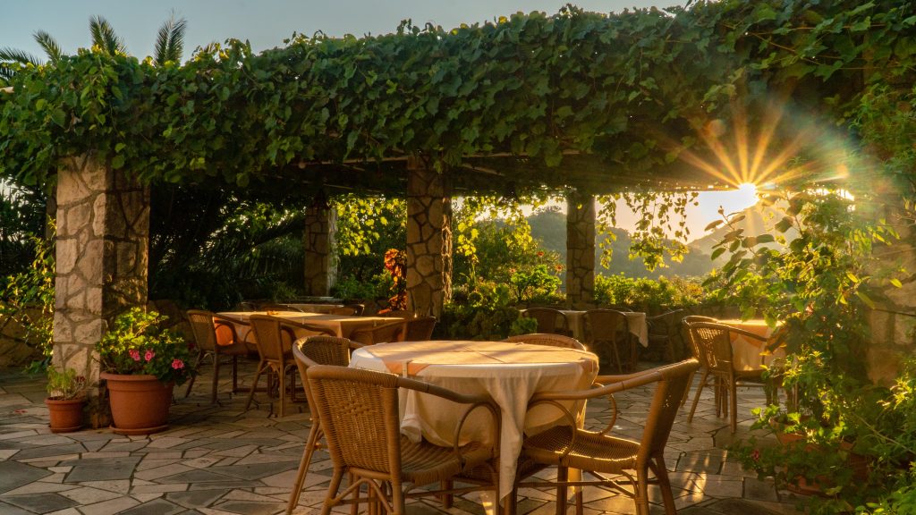 The sun sets on a garden with an outdoor dining area.