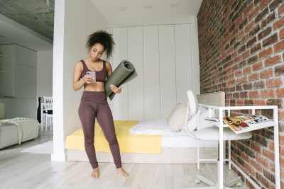 A young woman checks her smartphone messages before starting her home workout.