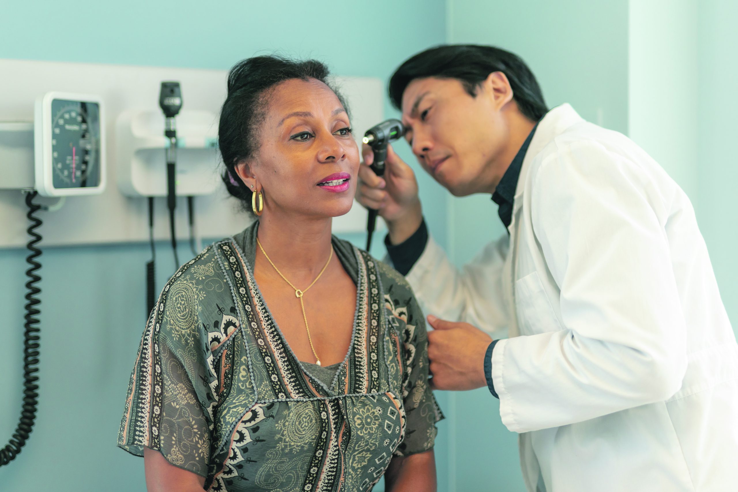 In a clinic, a Korean doctor examines a patient's ears for hearing loss.