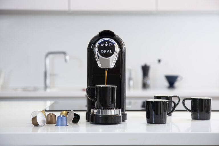 A black Opal One Pod Machine from Artisan Coffee Co in a white kitchen.