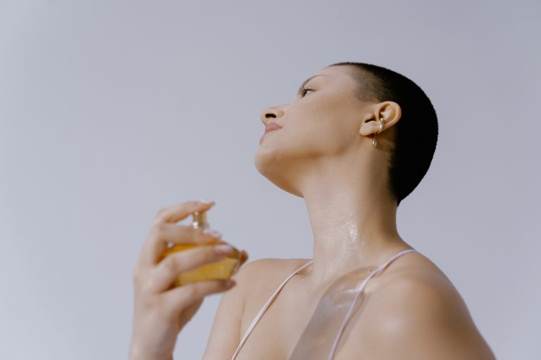 A young woman with cropped hair mists herself with a celebrity perfume.