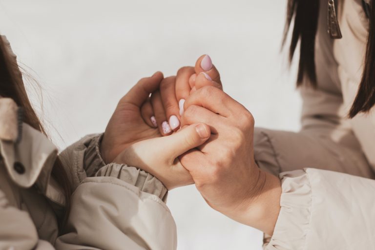 A mother's hands holding onto her teenager's hands.