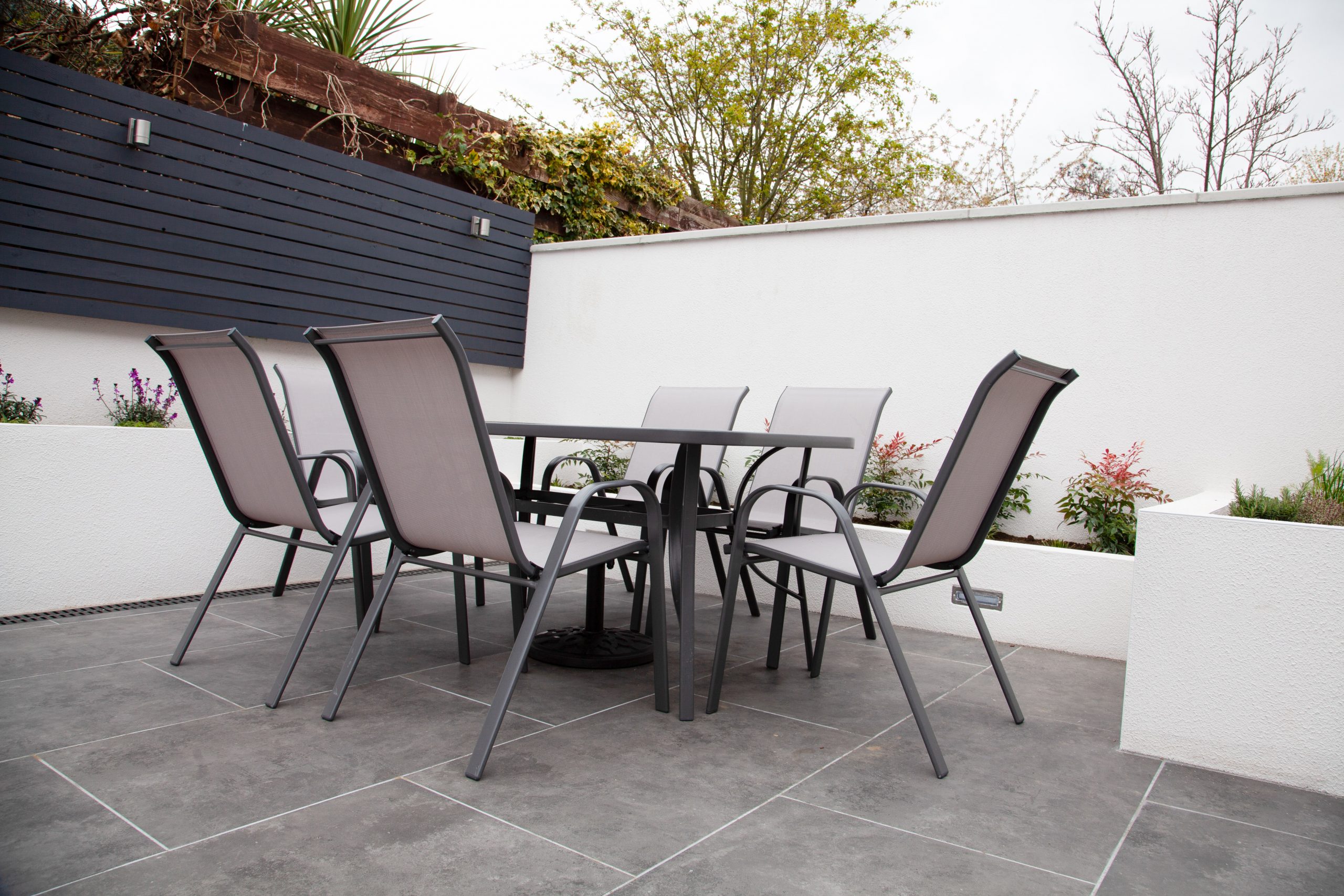 A garden seating area tiled with grey marble slabs.