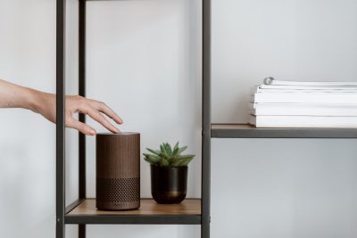 A woman switches on her Amazon Echo speaker resting on a shelf.