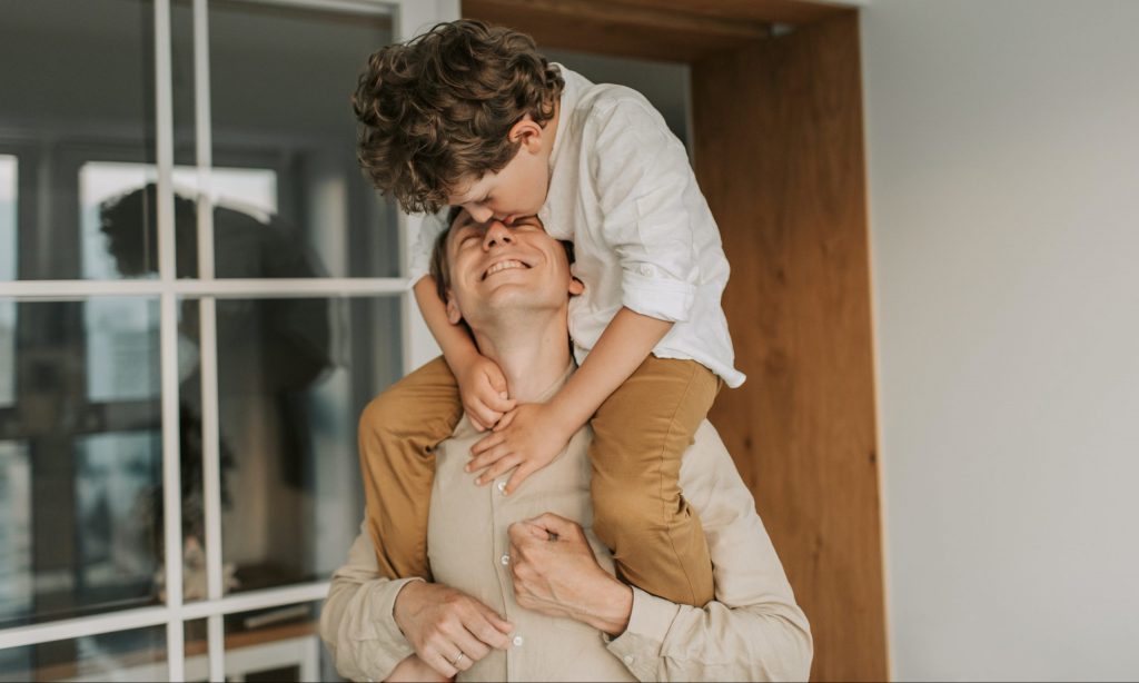 A young boy riding his father piggyback.