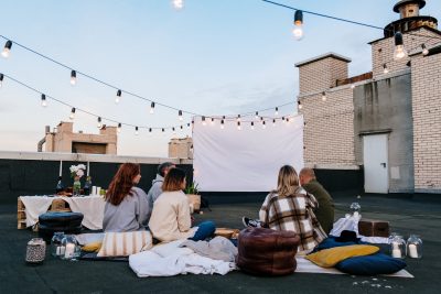 Group of friends sitting on the lawn to watch a film outdoors