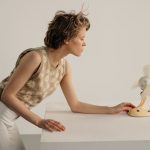 A young woman switching on a small fan to stay cool.