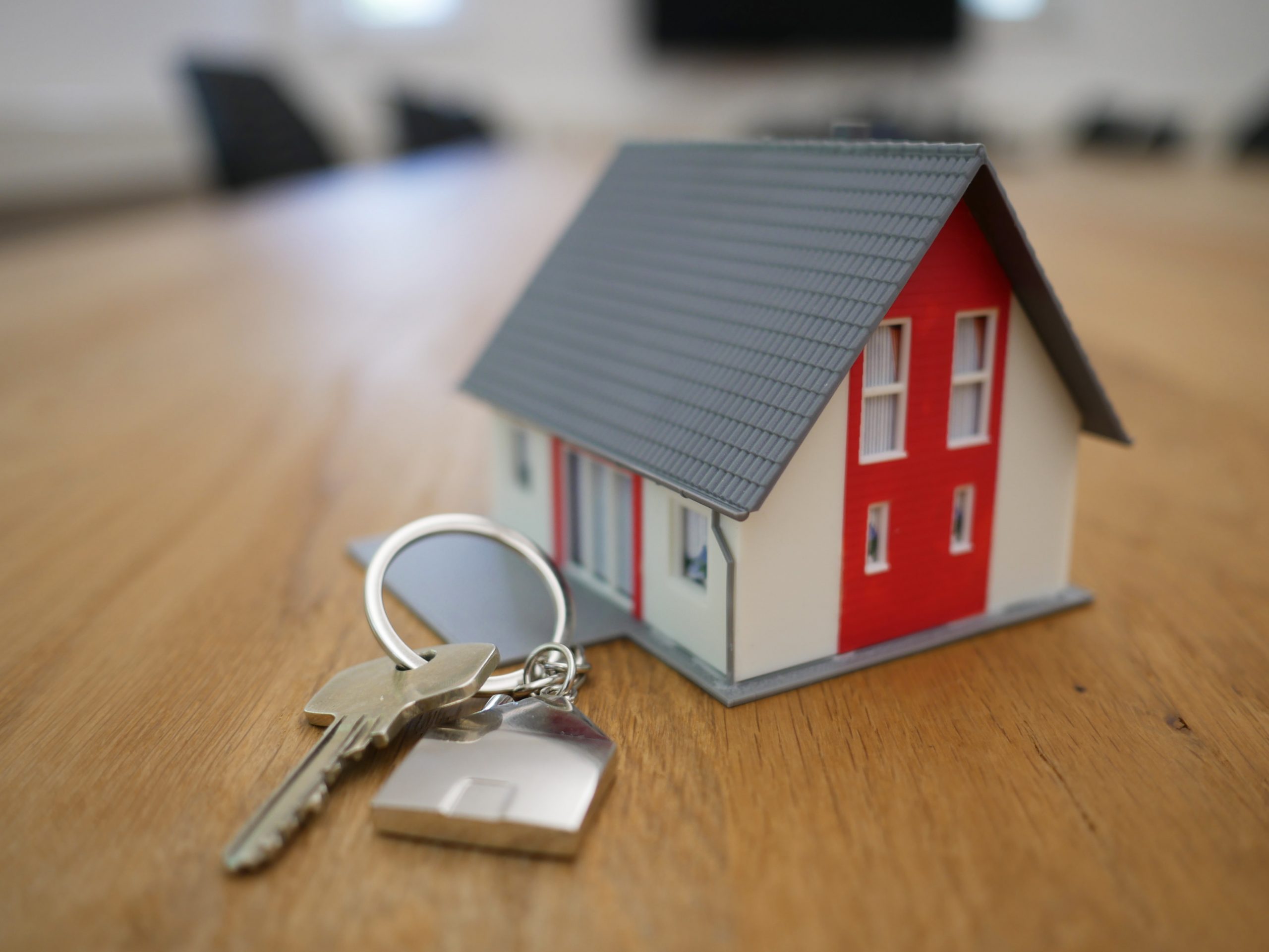 A small model of a house next to a set of keys in a showroom office.
