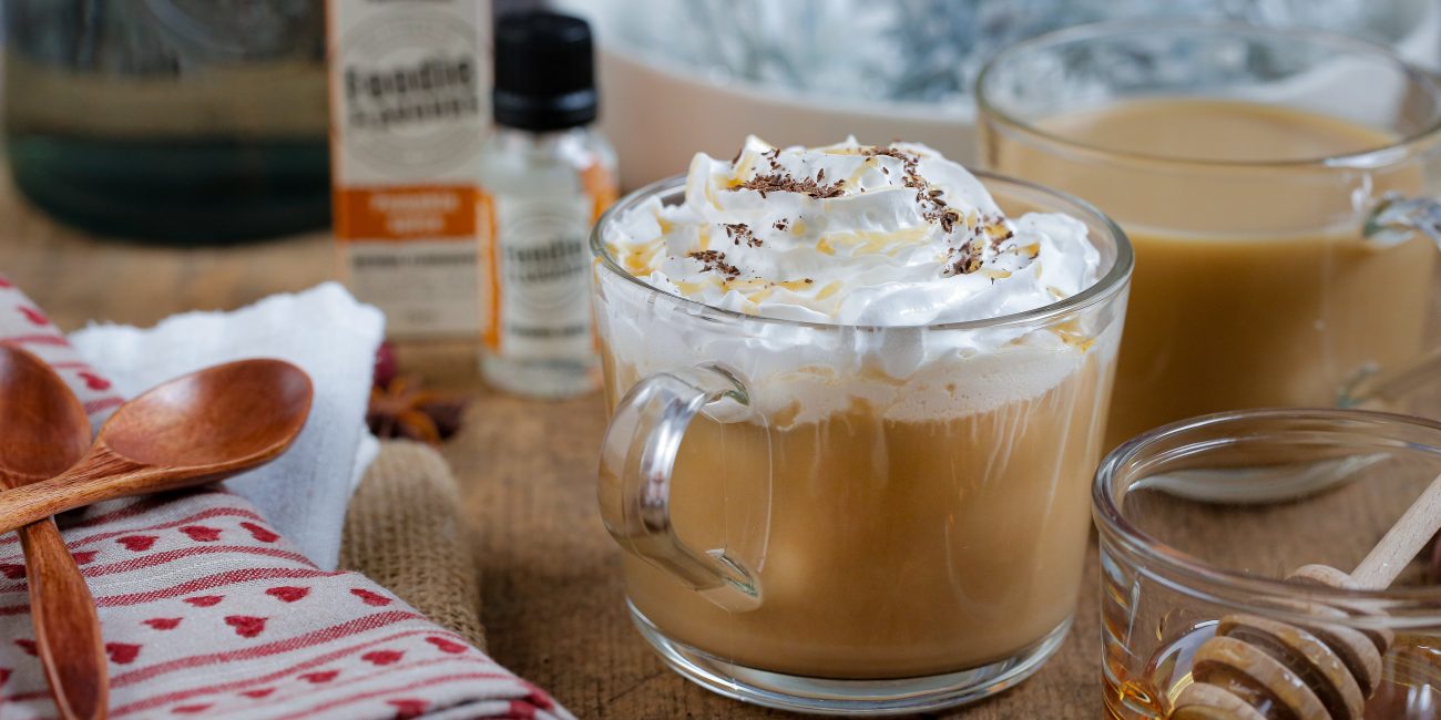 Pumpkin spiced latte in a glass mug surrounded by recipe items