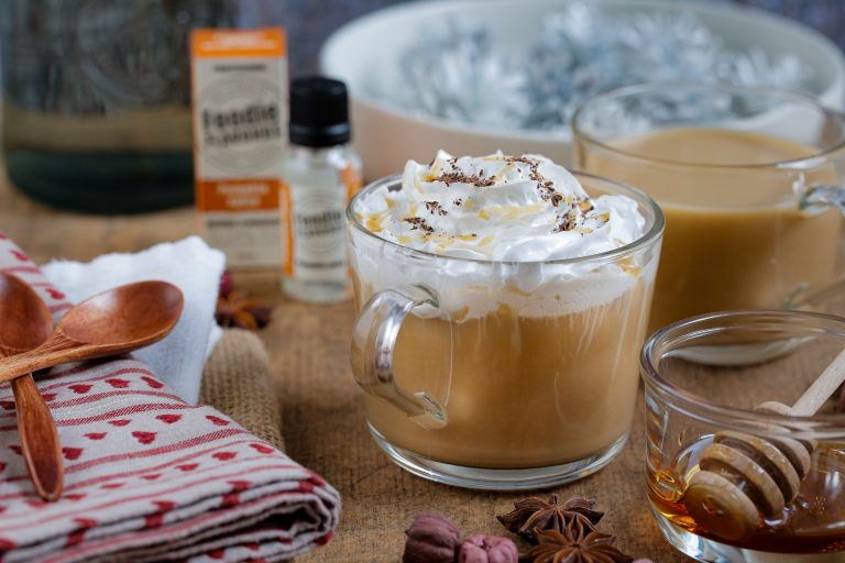 Pumpkin spiced latte in a glass mug surrounded by recipe items