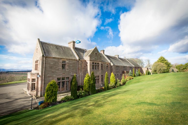 A scenic view of MurraysHall Hotel in the Scotland hills.