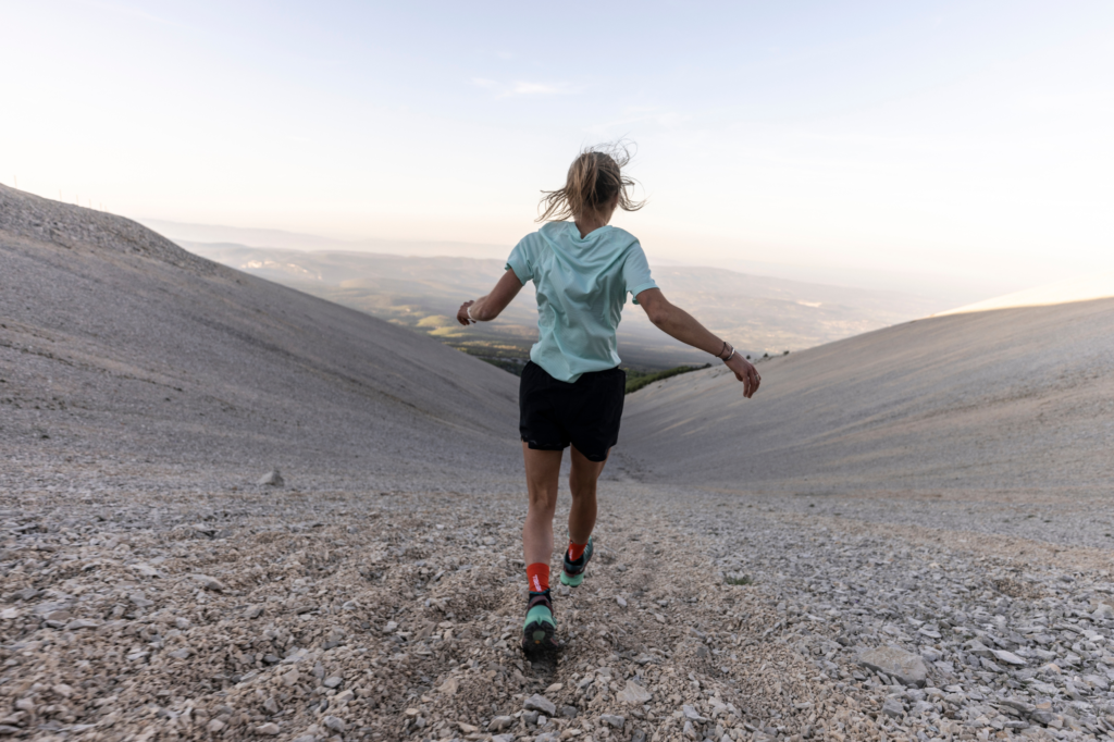 A young female jogger runs through a barren landscape.