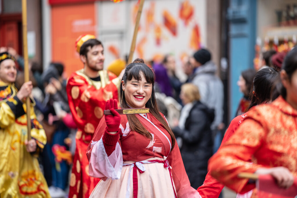 A woman in the Chinese New Year parade smiles and waves in Chinatown, London.