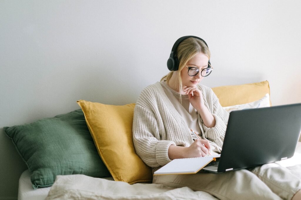 A woman takes notes listening to a podcast on ‘how to manage imposter syndrome?’.