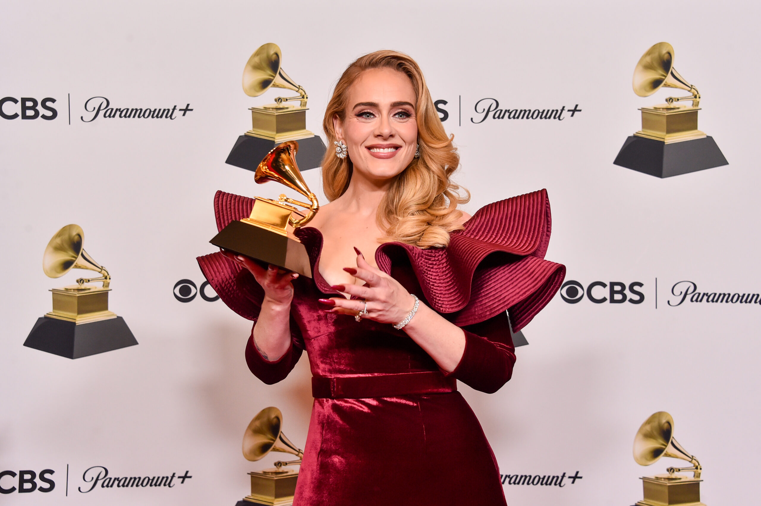 Dressed in a stylish red designer dress, singer Adele poses for the cameras with her award at the 65th GRAMMY Awards.