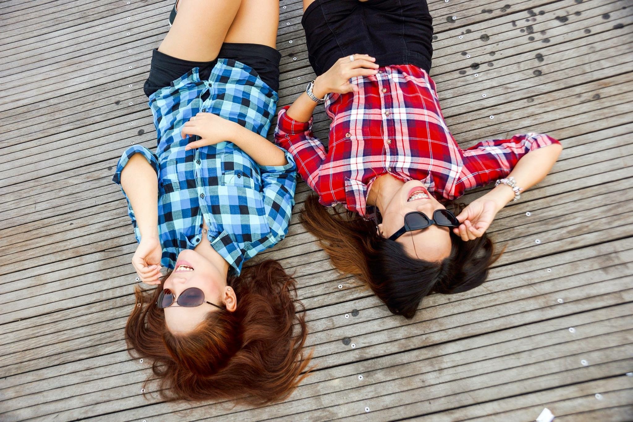 Lying on the ground, two friends hang out with their shades on.