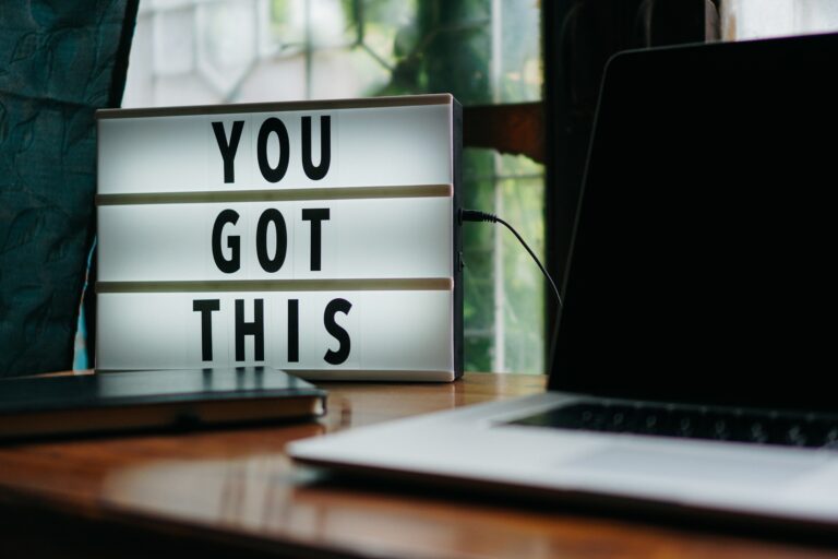 A small electric sign on a desk with a MacBook reads: 'YOU GOT THIS'.