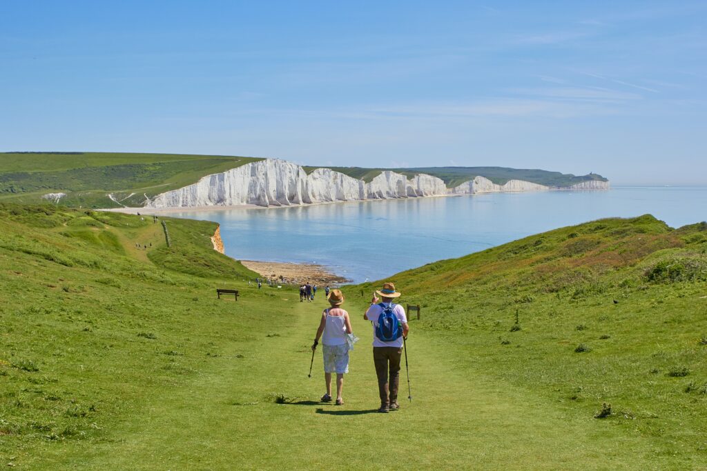 Old couple walking on green grass towards the Seven Sisters