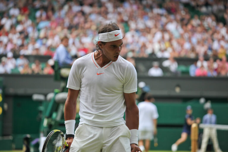 A tennis player takes their stance to serve at Wimbledon.