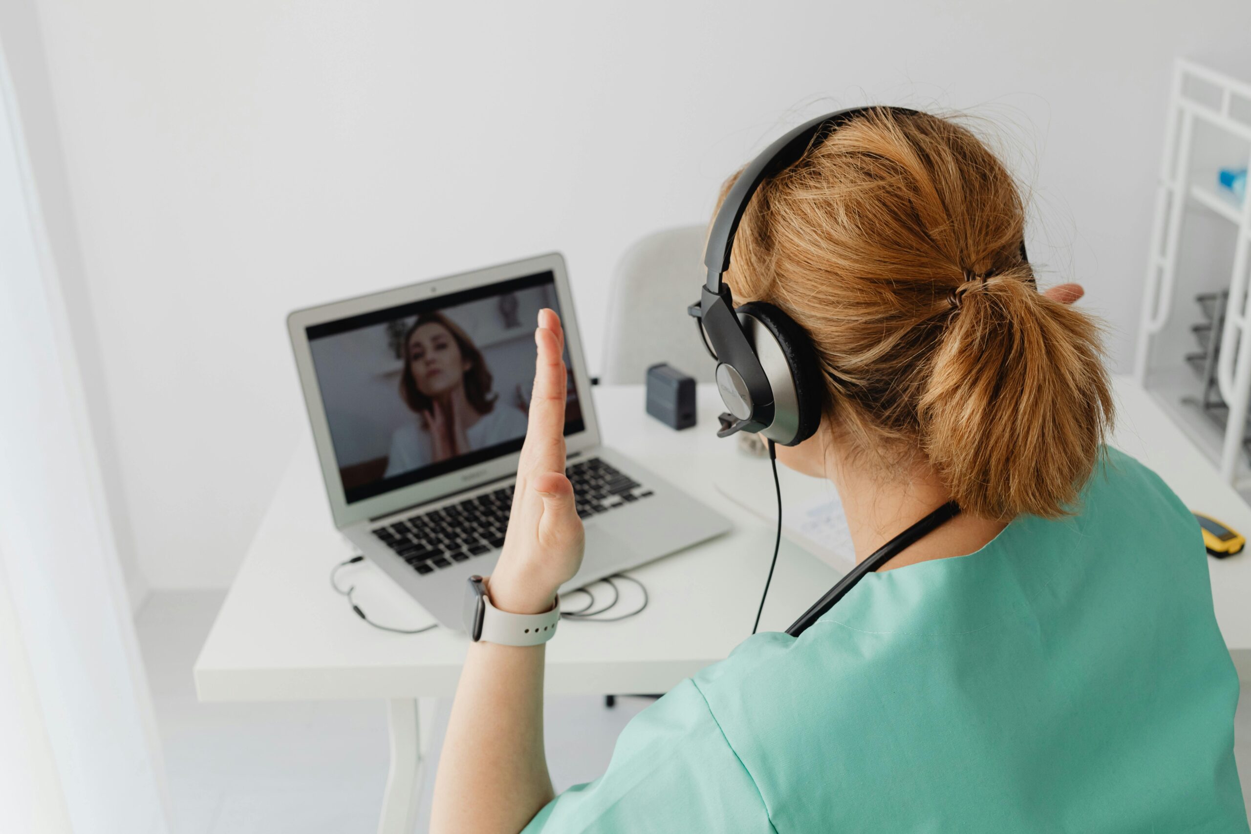 Doctor in green scrubs on laptop video call with patient