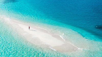 Travel lover walking on white sand strip in the Maldives
