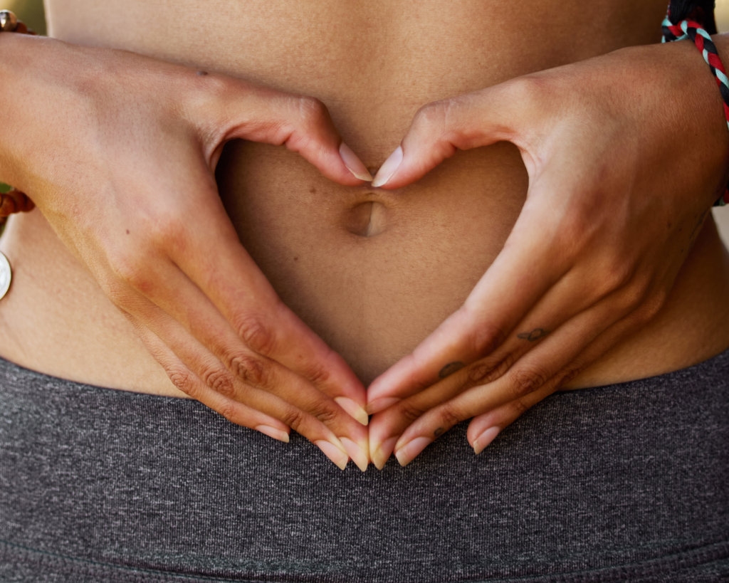 Woman making heart in hands over stomach