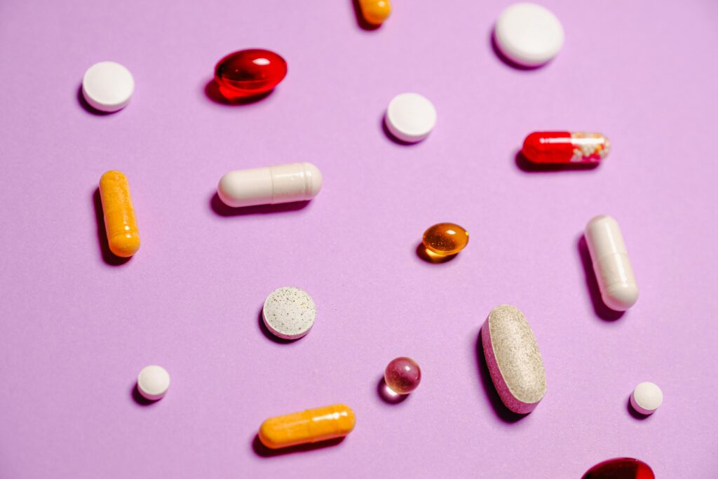A pink background with different supplements and vitamins scattered across it