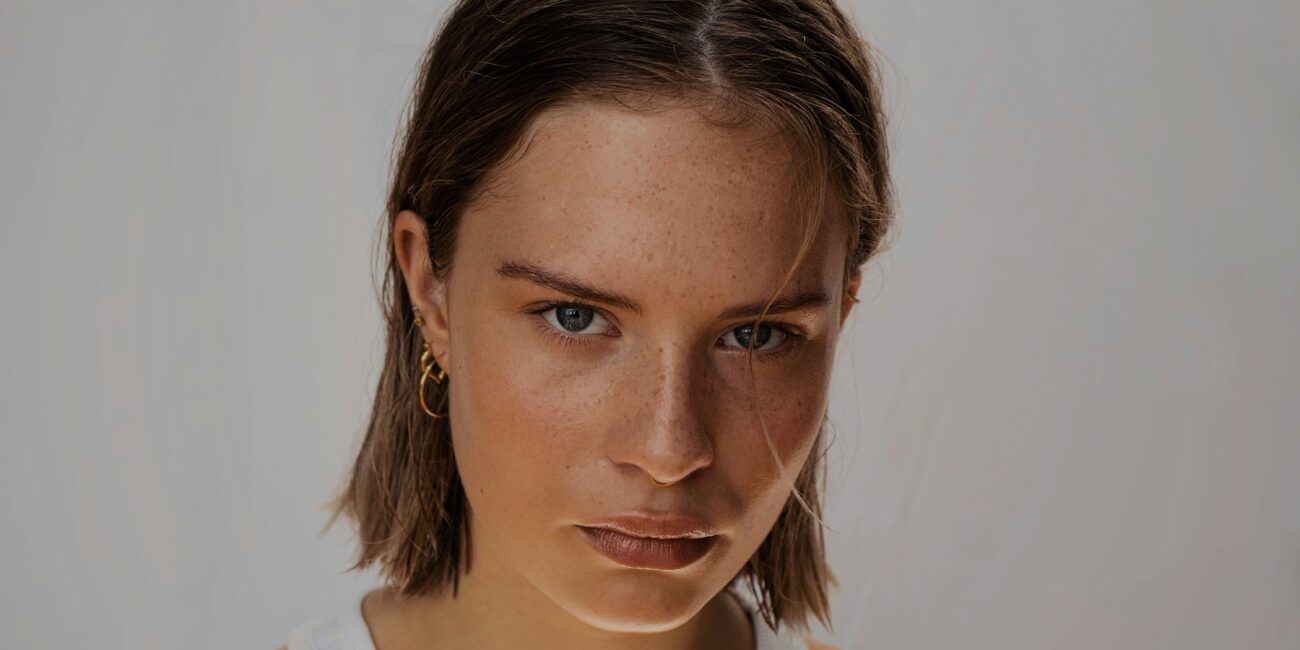 A woman with a heavy brow looks into the camera lens