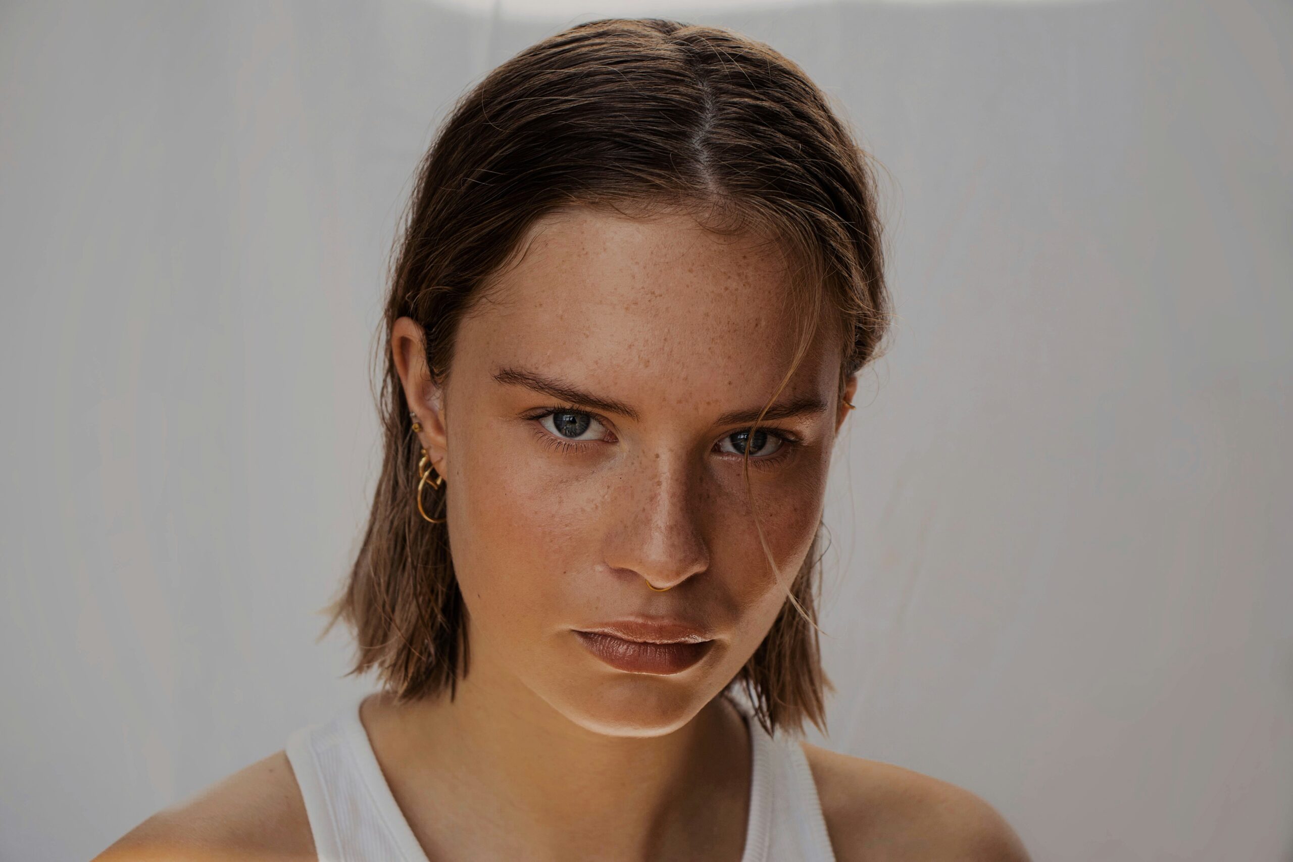 A woman with a heavy brow looks into the camera lens