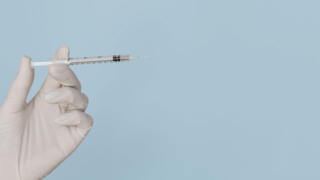 a needle ready to inject polynucleotides held against a blue background