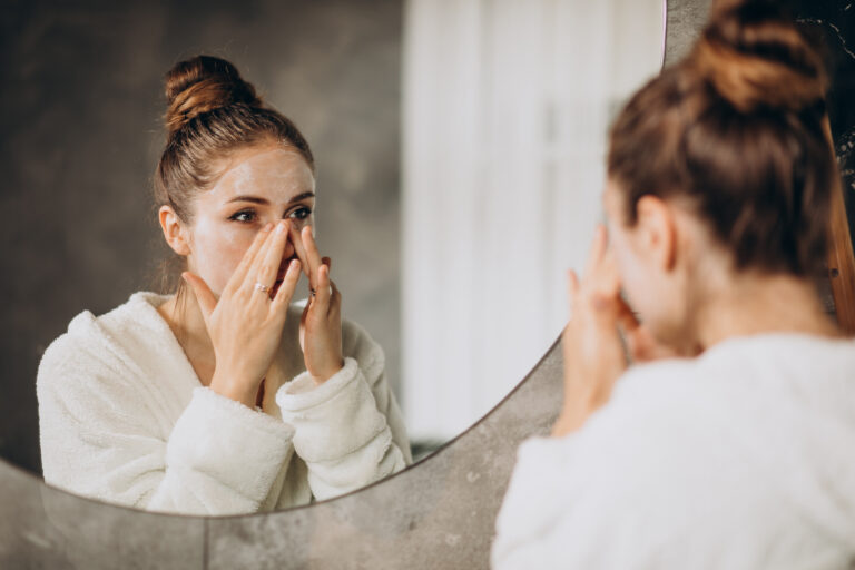 A woman looks in the mirror as she washes her face with a milky cleanser