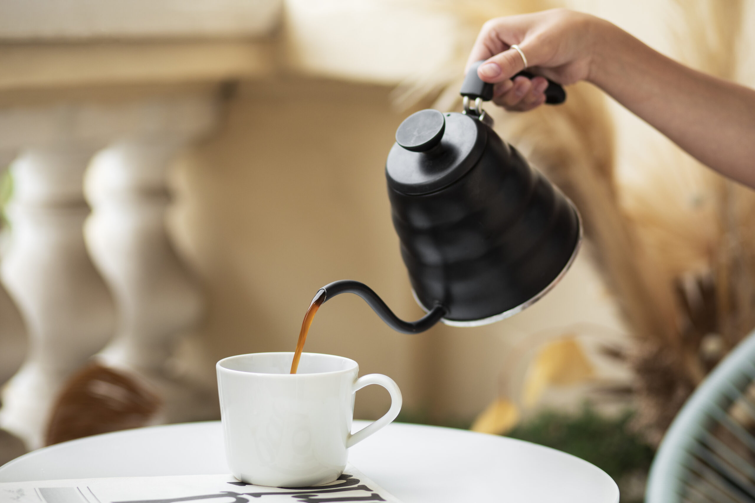 a hand pours shilajit tea out of a pot into a cup