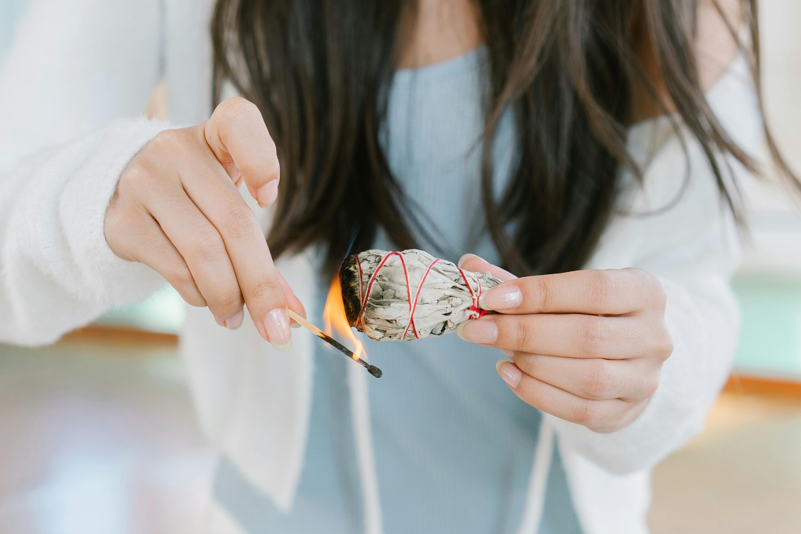 A woman lights some sage to smudge her home