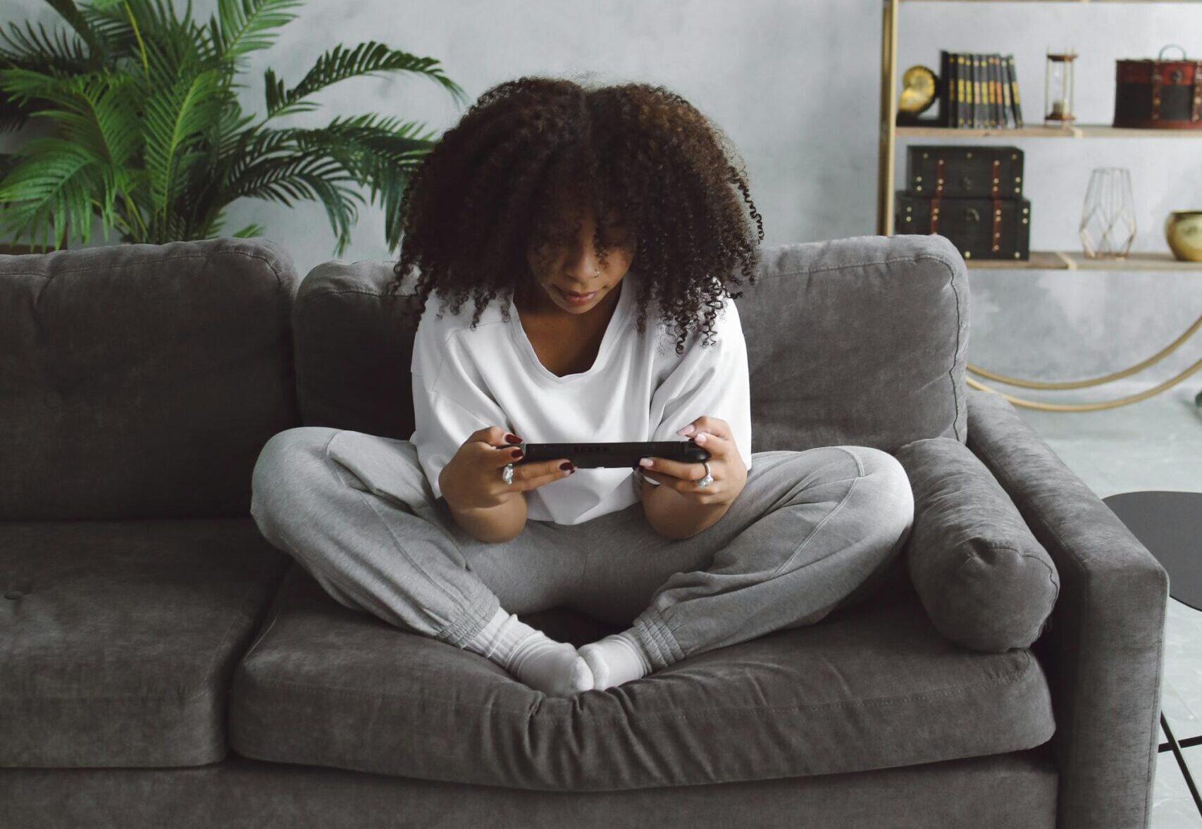 a woman looking cosy gaming on a sofa with a Nintendo switch