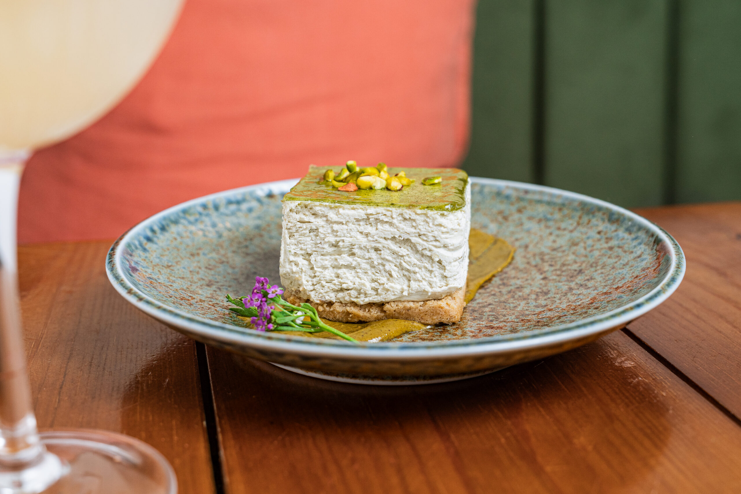 plate with square of white dessert with green top and a flower