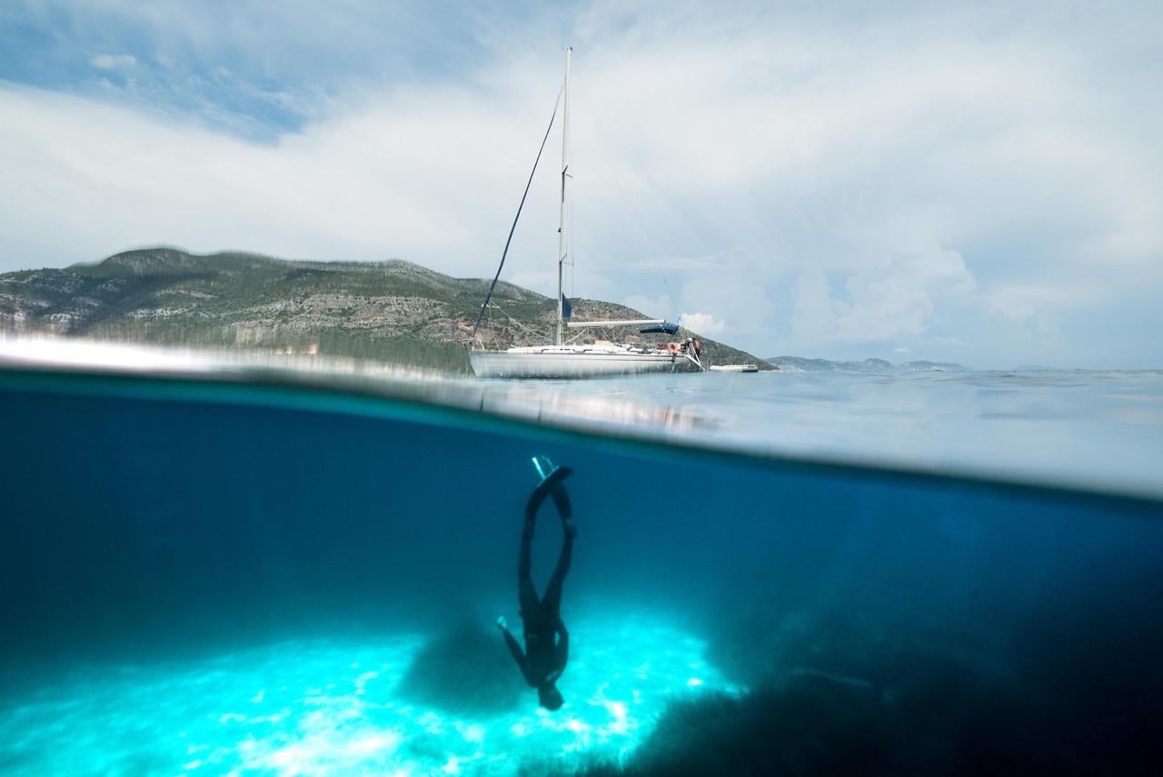 figure diving underneath boat in ocean in Greece