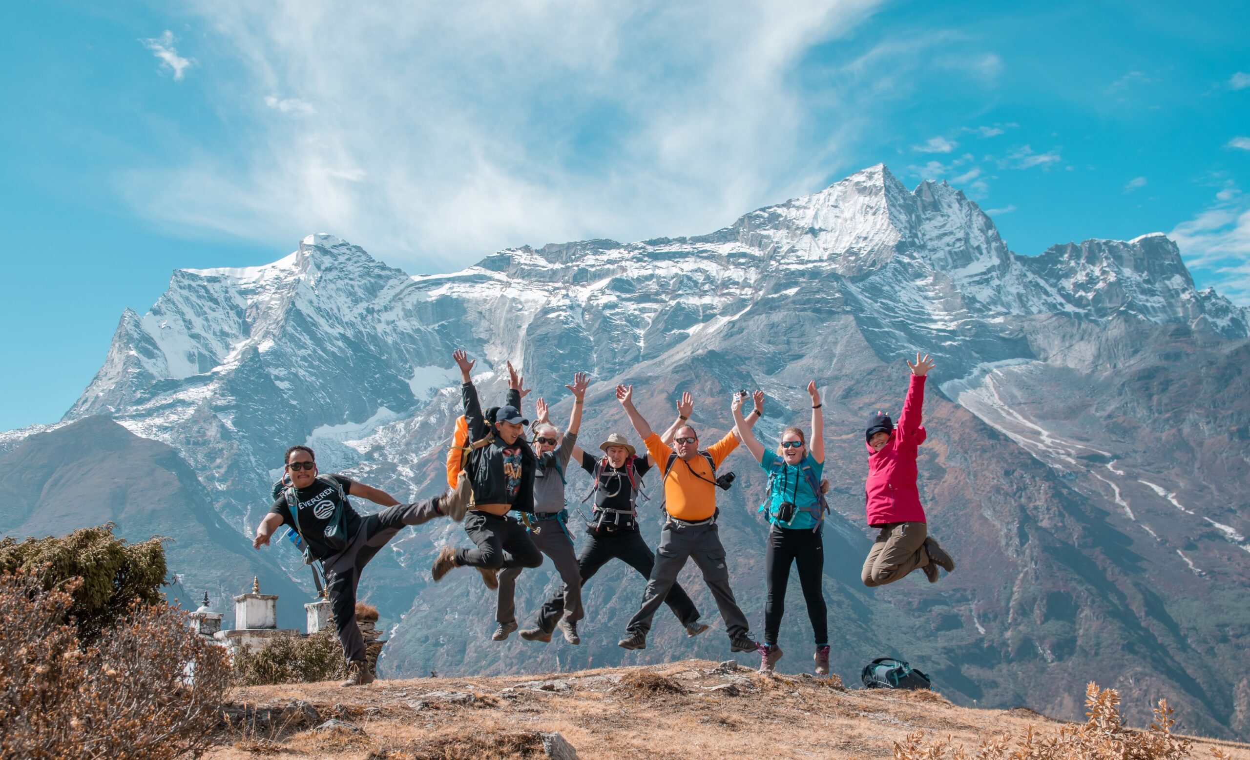 Group of people jumping up and smiling with mount Everest as backdrop