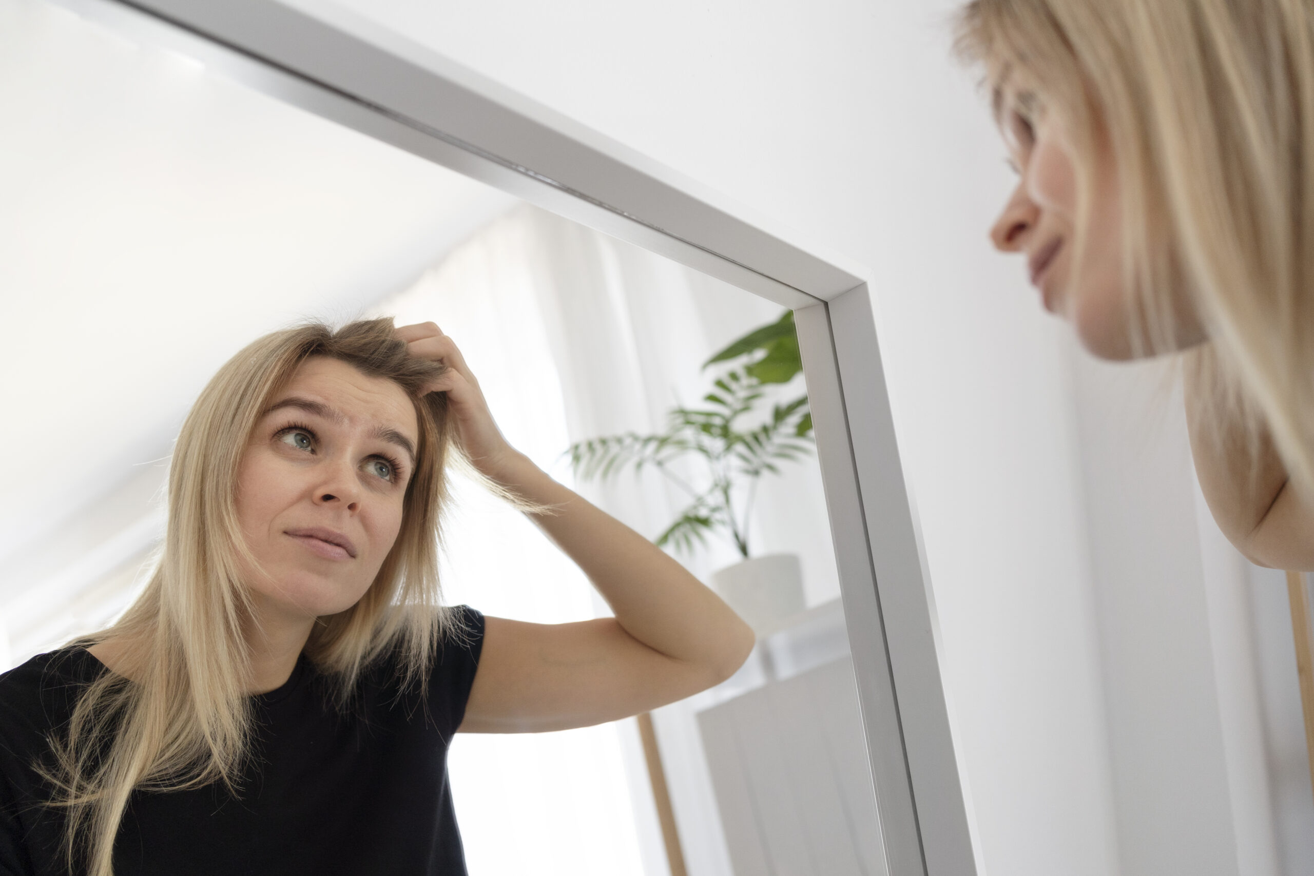 Woman looks at her frown lines in the mirror