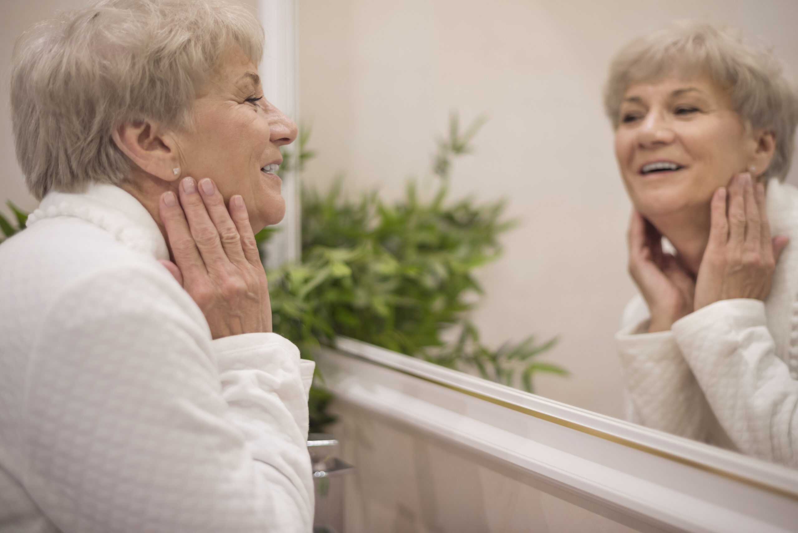 Elderly woman smiles in the mirror