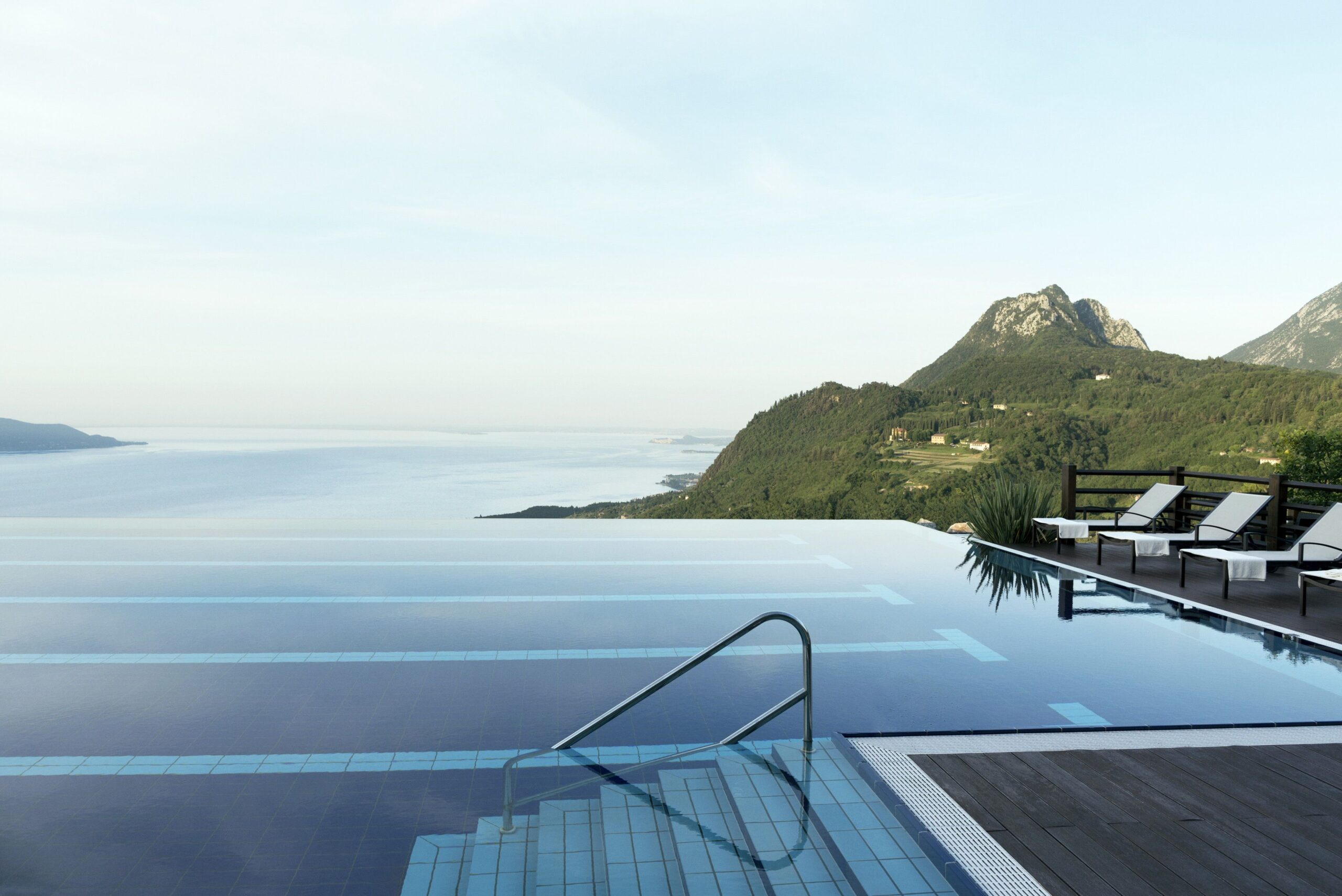 Infinity pool with deck chairs overlooking mountain hills