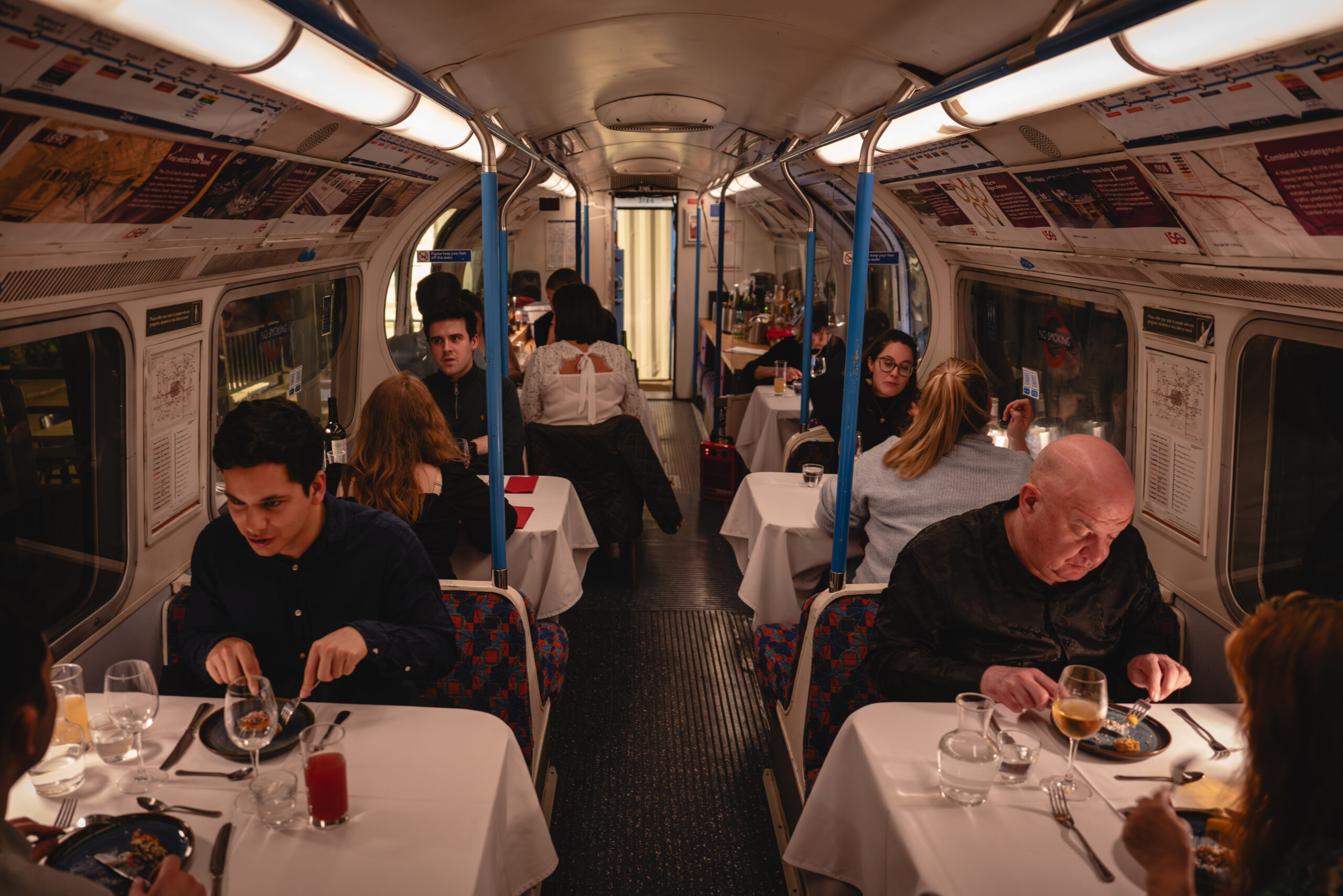 old tube carriage with tables and linens and people sitting eating dinner out