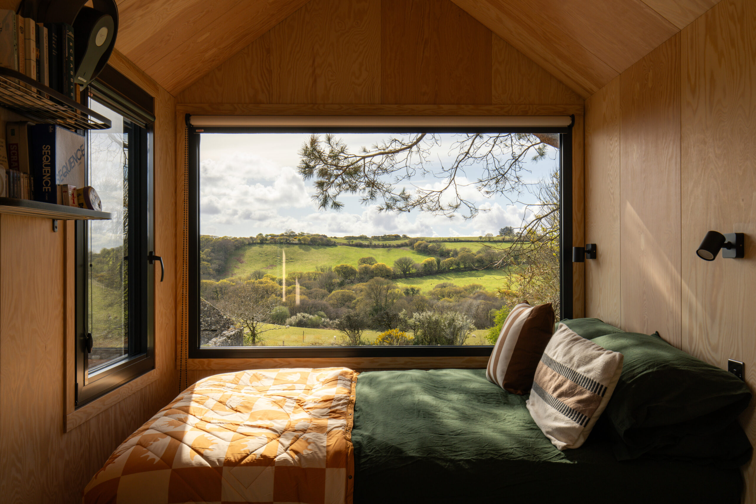 bed beneath a wooden cabin with a view facing fields and trees