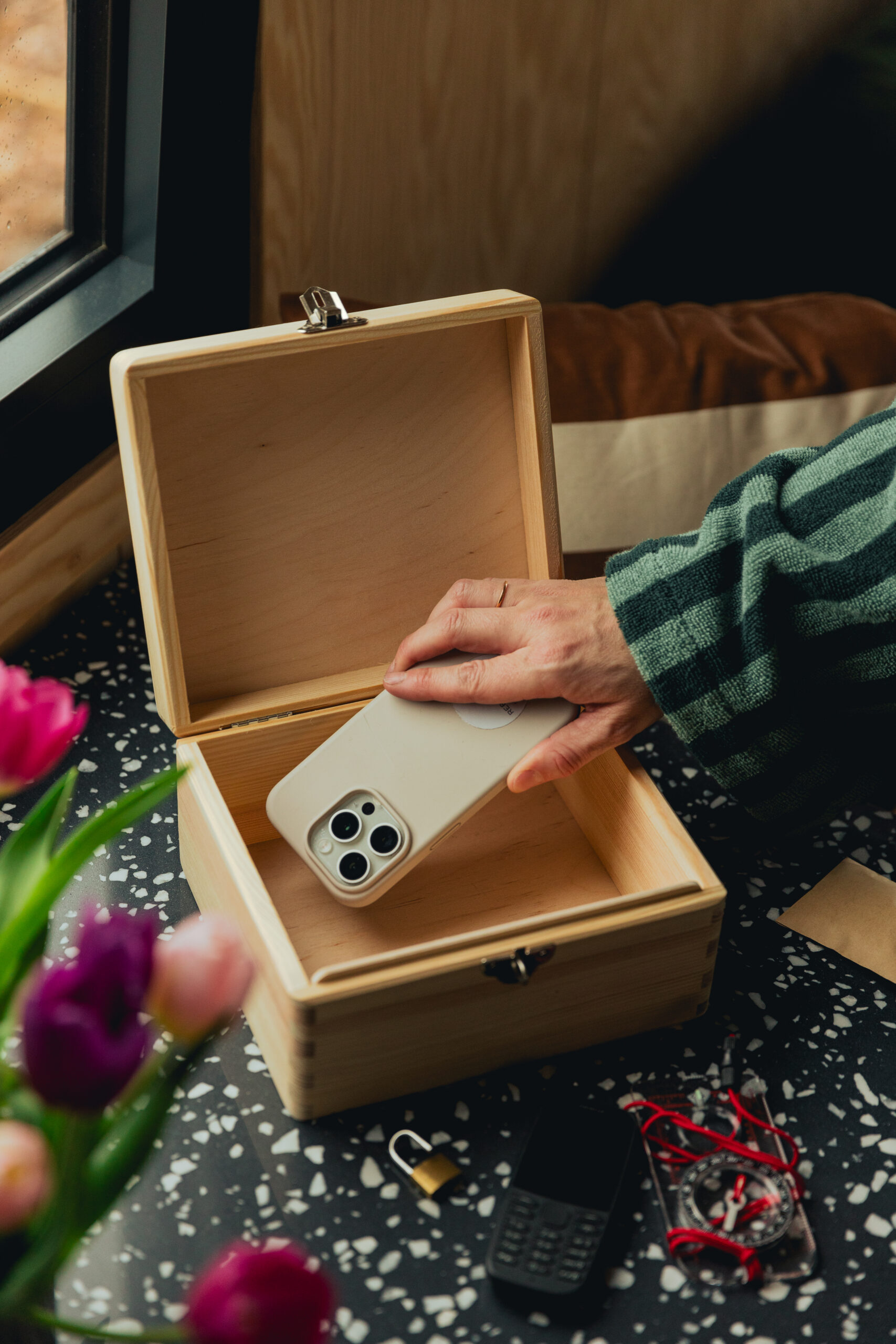 wooden lockbox, open, with a person putting a phone inside