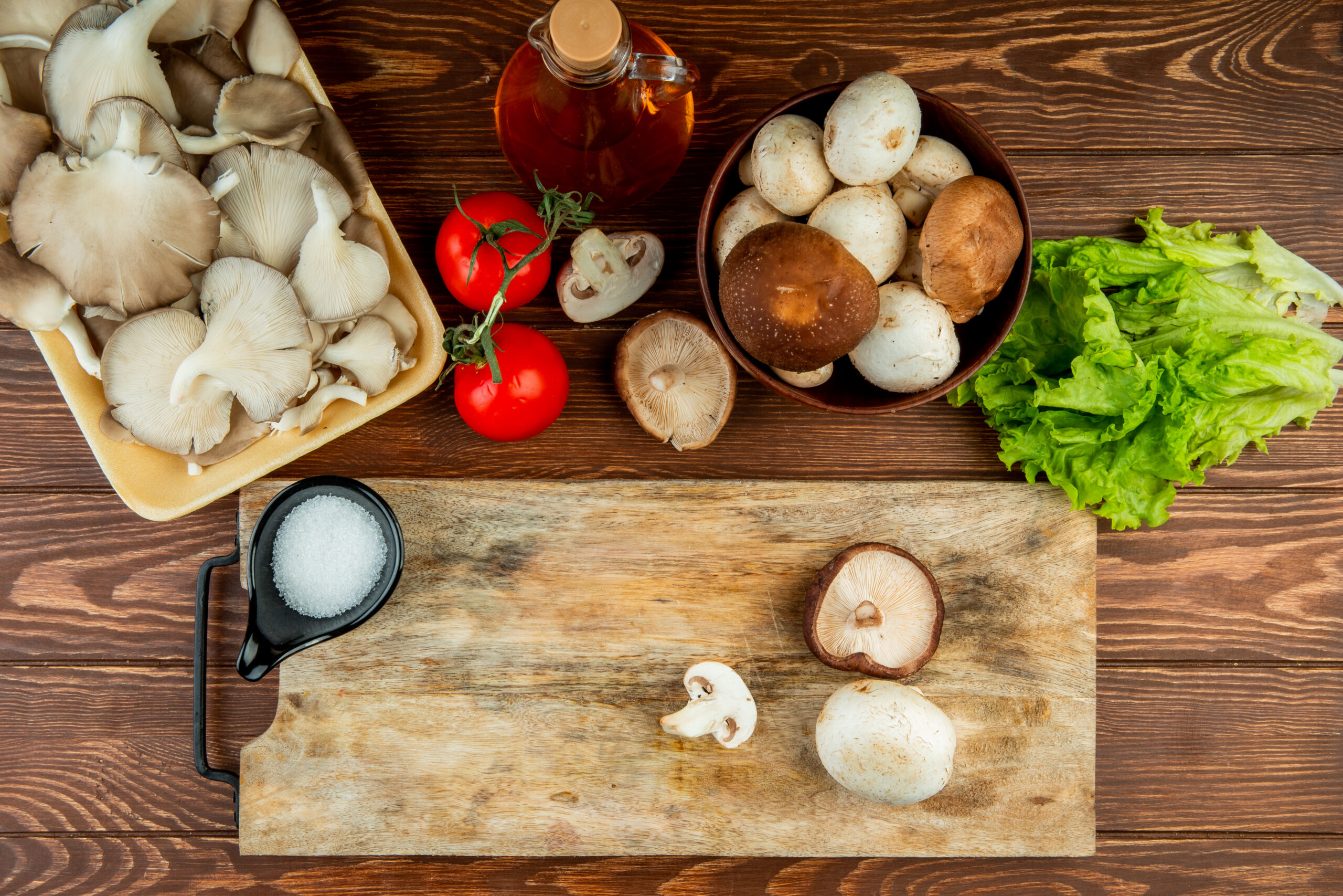 Top view table with chopping board with mushrooms being chopped, and lettuce
