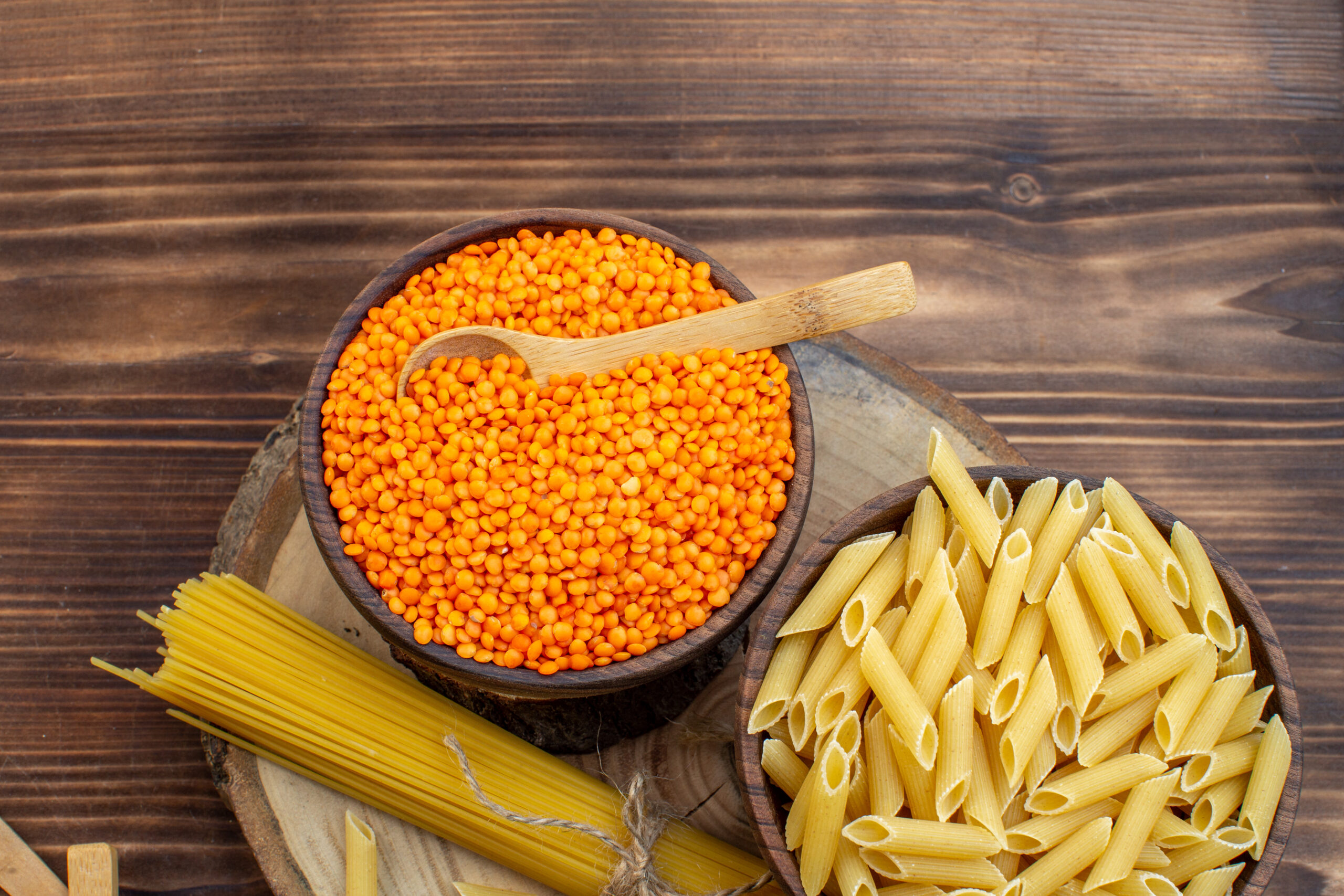 top view of wooden tabletop with bowl of lentils, bowl of pasta and spaghett8