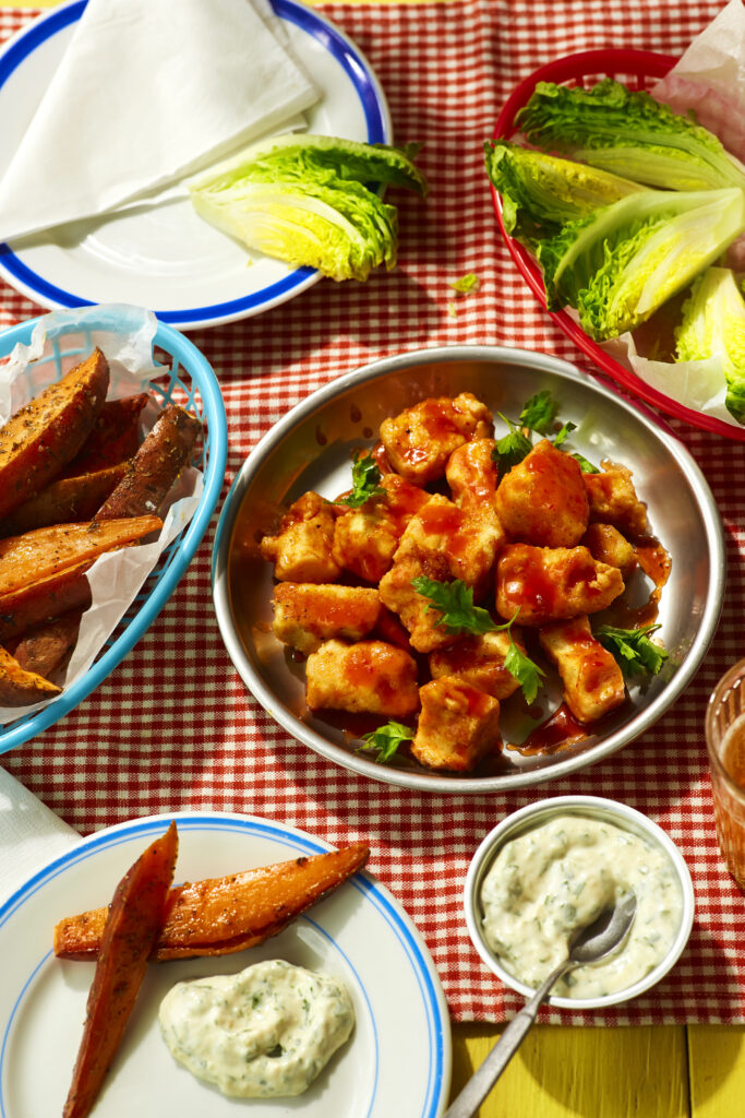 top down slanted view of plates and bowls with tofu wings and dips