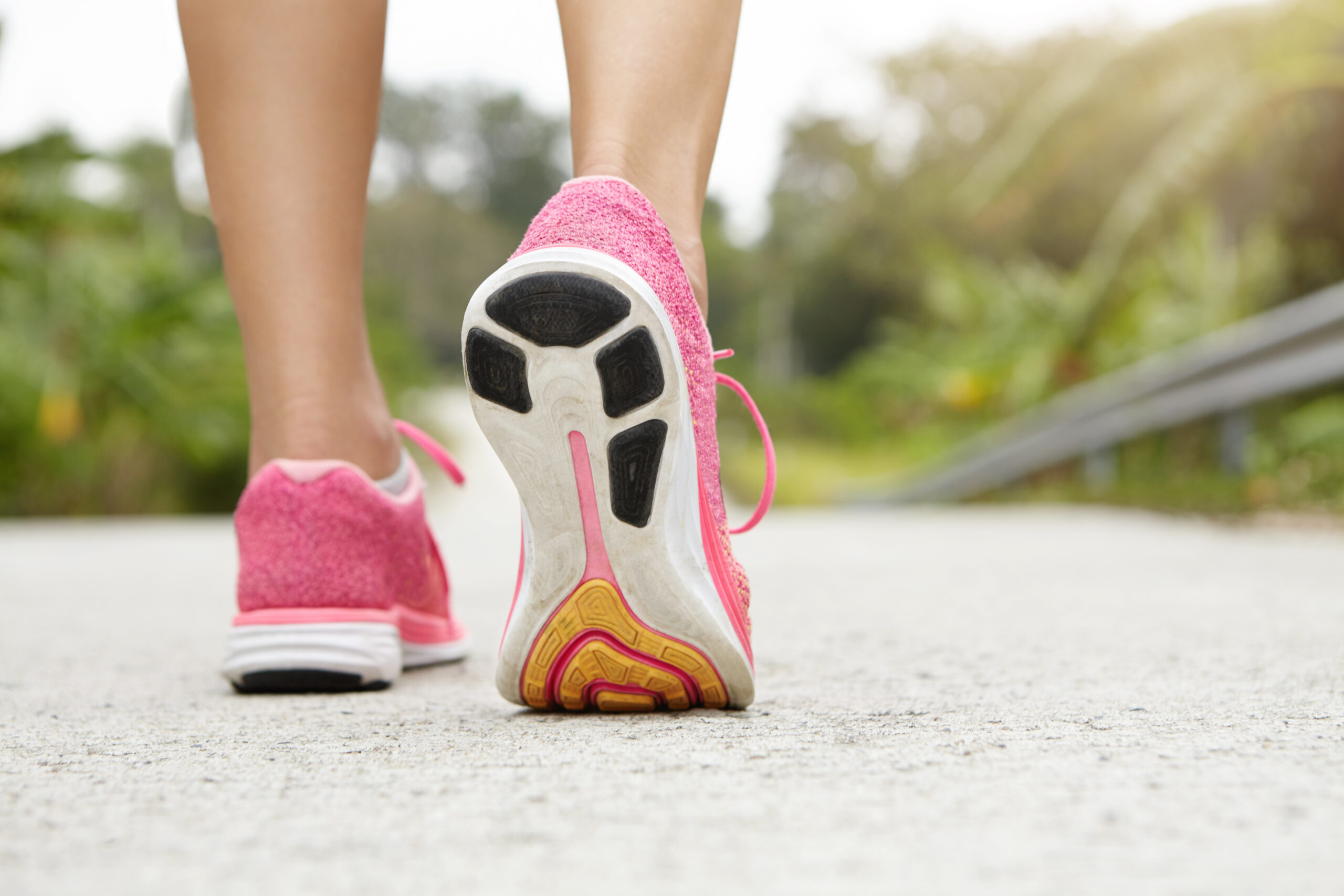 shot of woman's feet with trainers on walking from behind with pink trainers on